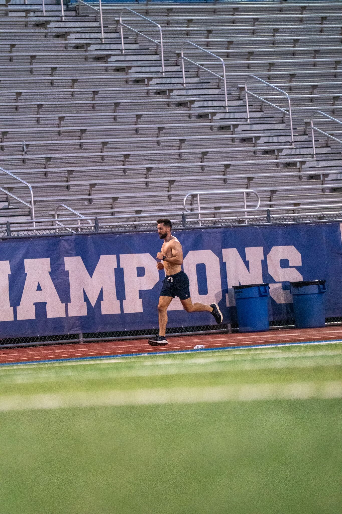 Caleb training on a track beside stadium bleachers